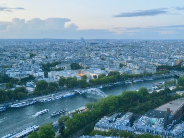 Scenic Paris skyline with Seine River at dusk, soft blue and orange hues, romantic ambiance