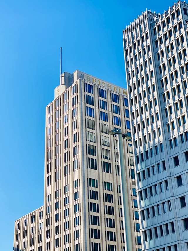Sunlit skyscrapers stand tall against a vibrant blue sky, creating a modern and urban atmosphere