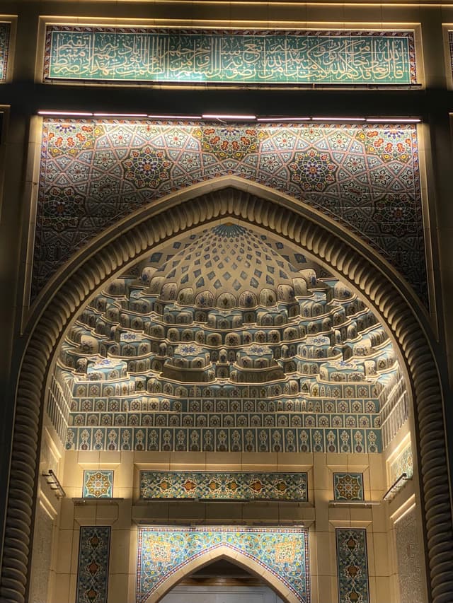 Elegant ornate archway with intricate tilework and patterns, bathed in warm, natural light, evoking a serene and historic atmosphere