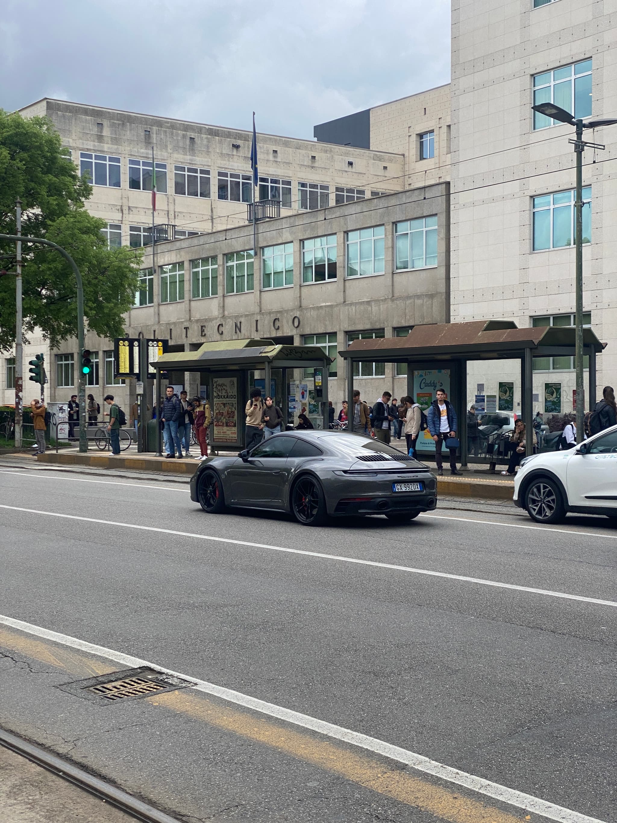 Bright sunlight on urban street with people, vehicles, and pastel buildings, creating lively, vibrant mood