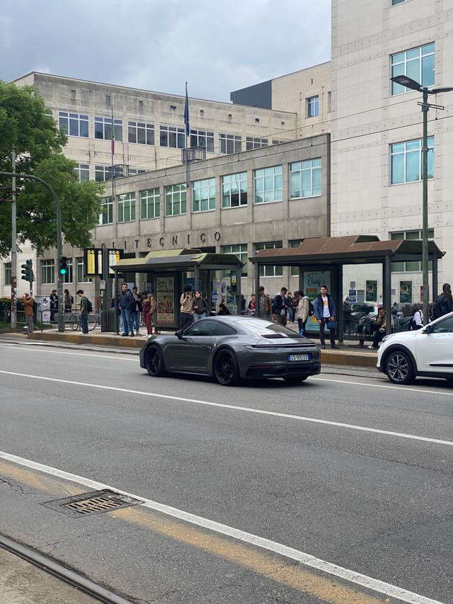 Bright sunlight on urban street with people, vehicles, and pastel buildings, creating lively, vibrant mood