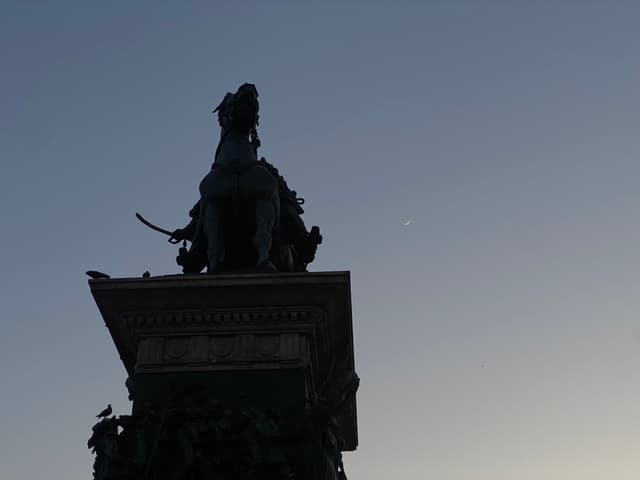 A serene night scene featuring a statue silhouetted against a starry sky, evoking a sense of timelessness and quiet contemplation