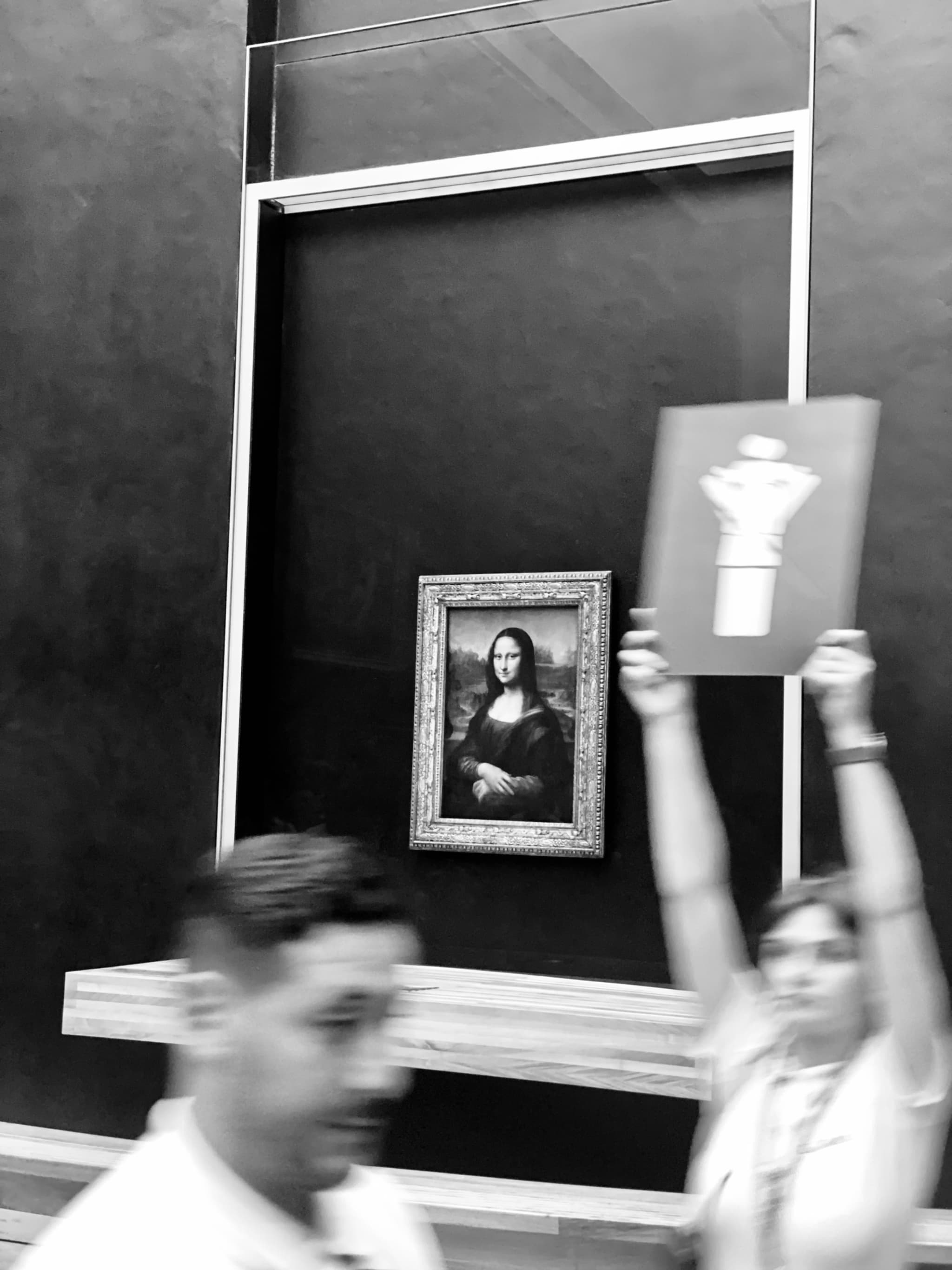 Silhouetted figures in a museum display, contrasted with a bright, iconic portrait in the back, evoking suspense and intrigue