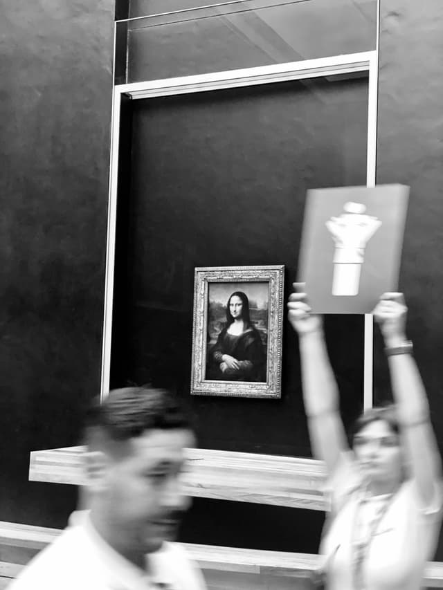 Silhouetted figures in a museum display, contrasted with a bright, iconic portrait in the back, evoking suspense and intrigue