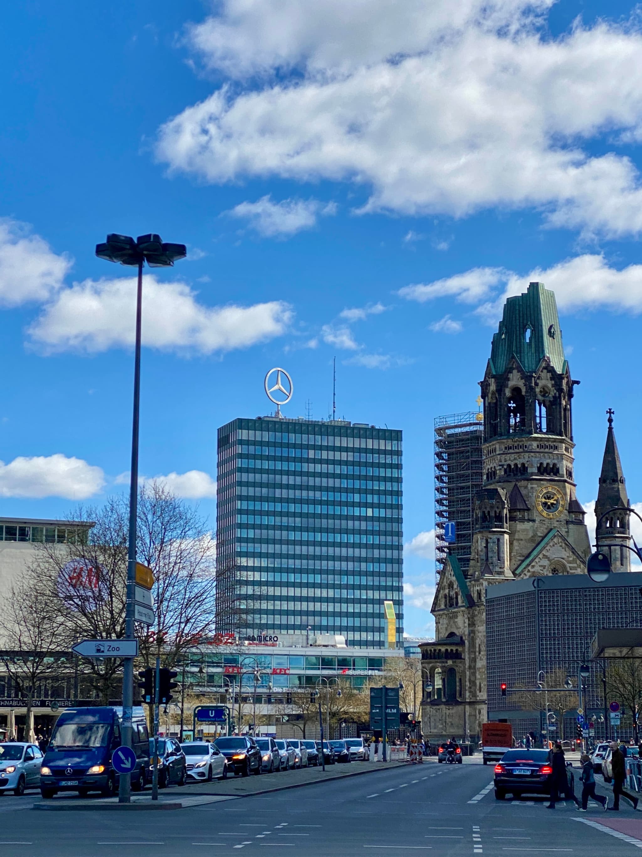 Modern Berlin cityscape under bright blue sky, Mercedes-Benz tower and historic church juxtapose old and new architecture
